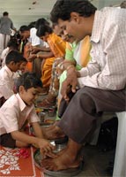 Children performing pada puja on their parents