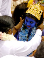 Amma with a child dressed up as Sri Krishna