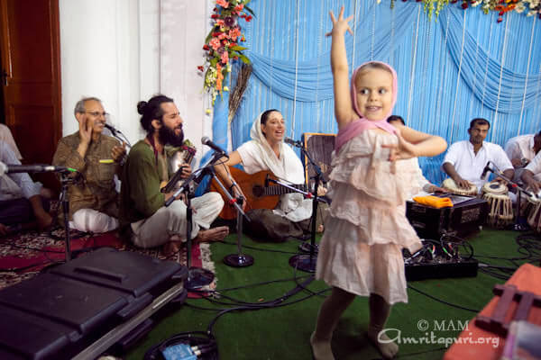 A little girl dancing spontaneously to a song while Amma is giving darshan