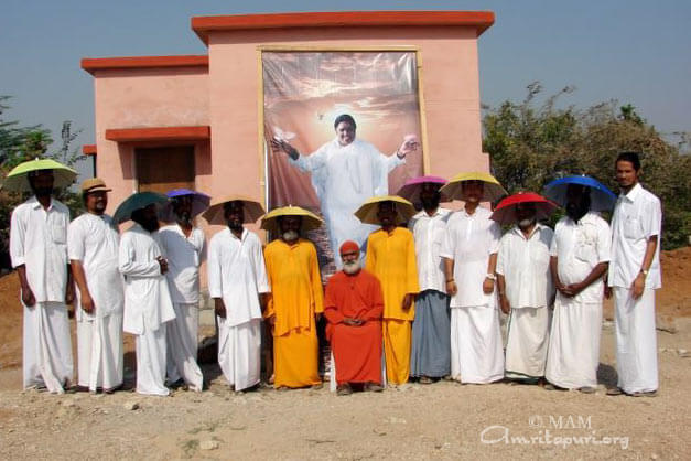 Swami Amritageetananda and brahamacharis in charge of construction with umbrella hat given by Amma