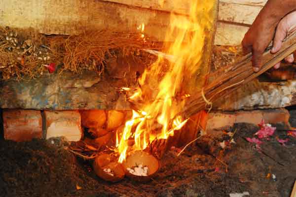 The fire is lit by Suresh, as per the traditional duty of the eldest son