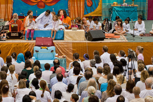 Sw. Ramakrishnananda is giving satsang; Amma with children on the stage