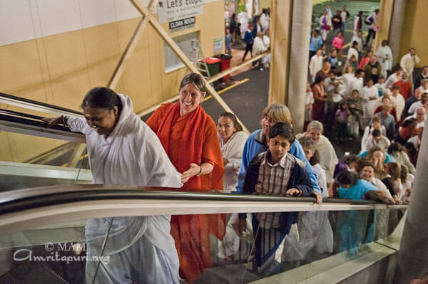 Amma and devotees on escalator to the dining hall during the retreat