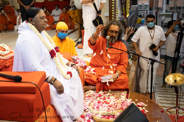 Swamiji offering flower petals at Amma's feet
